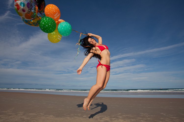 Young Woman at beach celebrating her birthday with Balloons on a Beach
